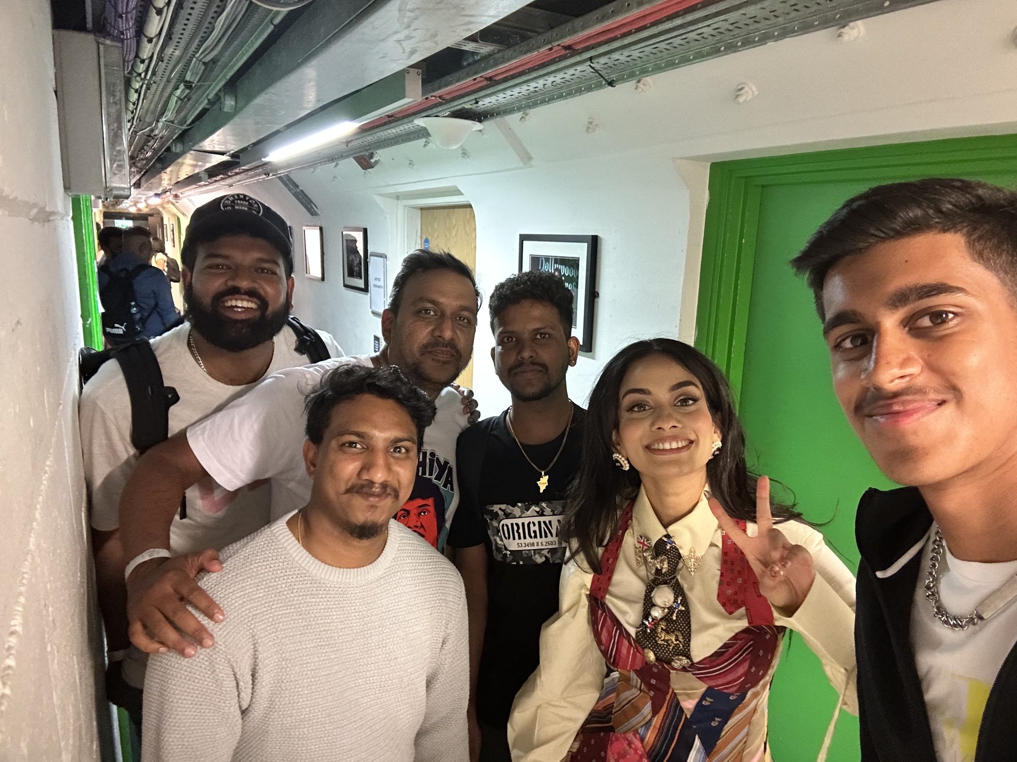 The group backstage in a green room corridor after a performance