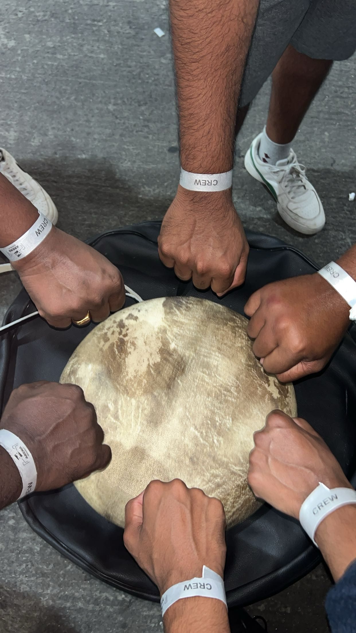 Close-up of two pairs of hands resting on a parai drum skin
