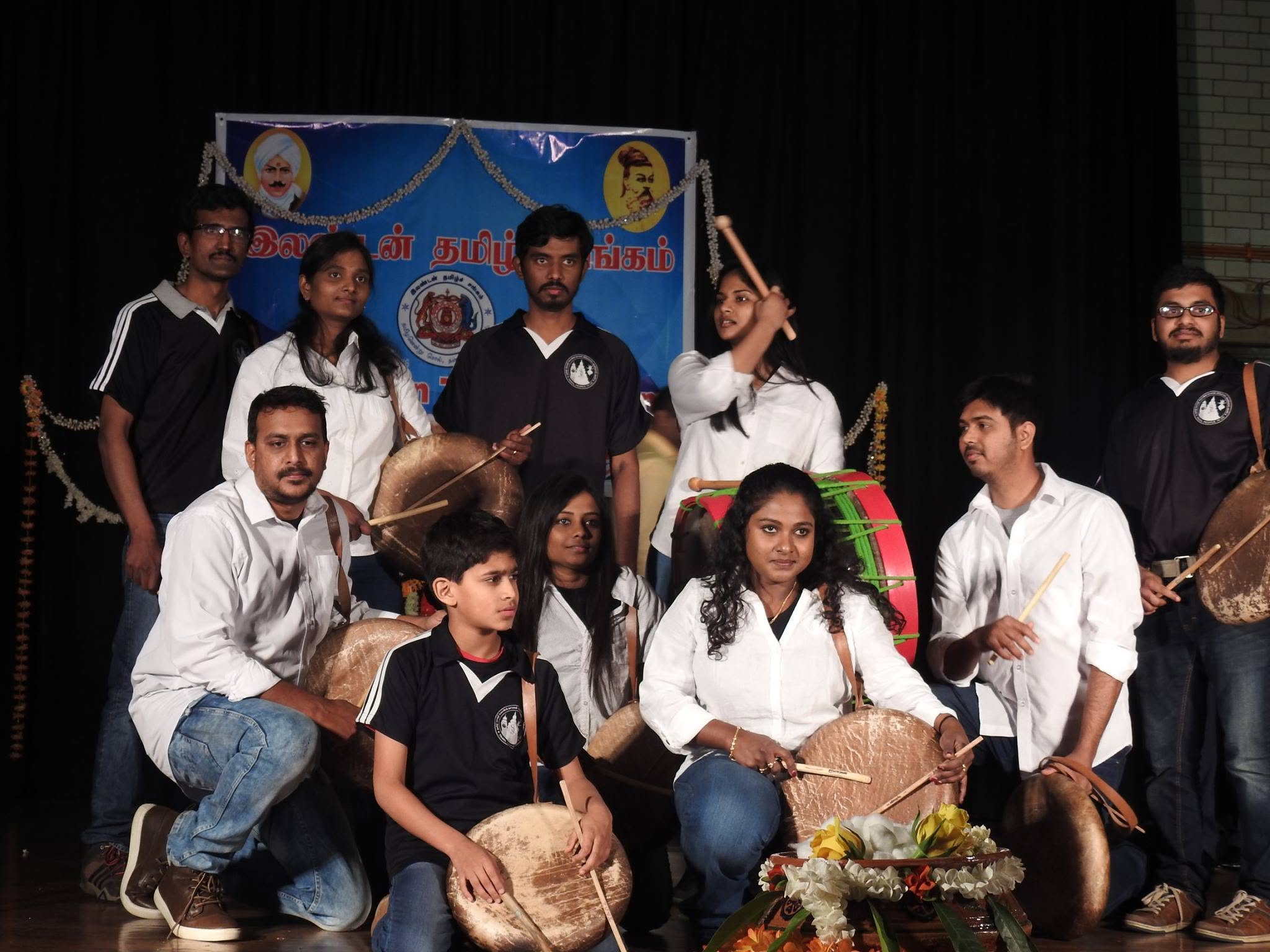 The group posed on stage with drums in front of a decorated backdrop