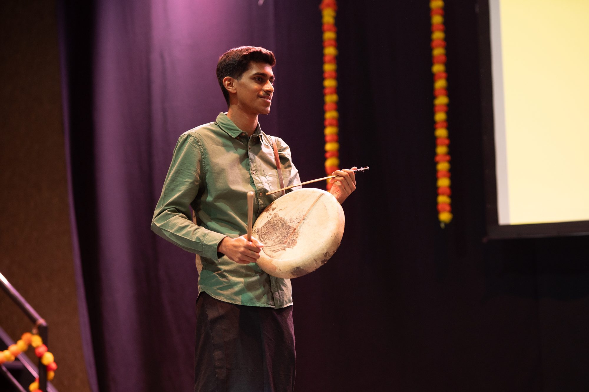 A young parai drummer performing alone on a darkened stage
