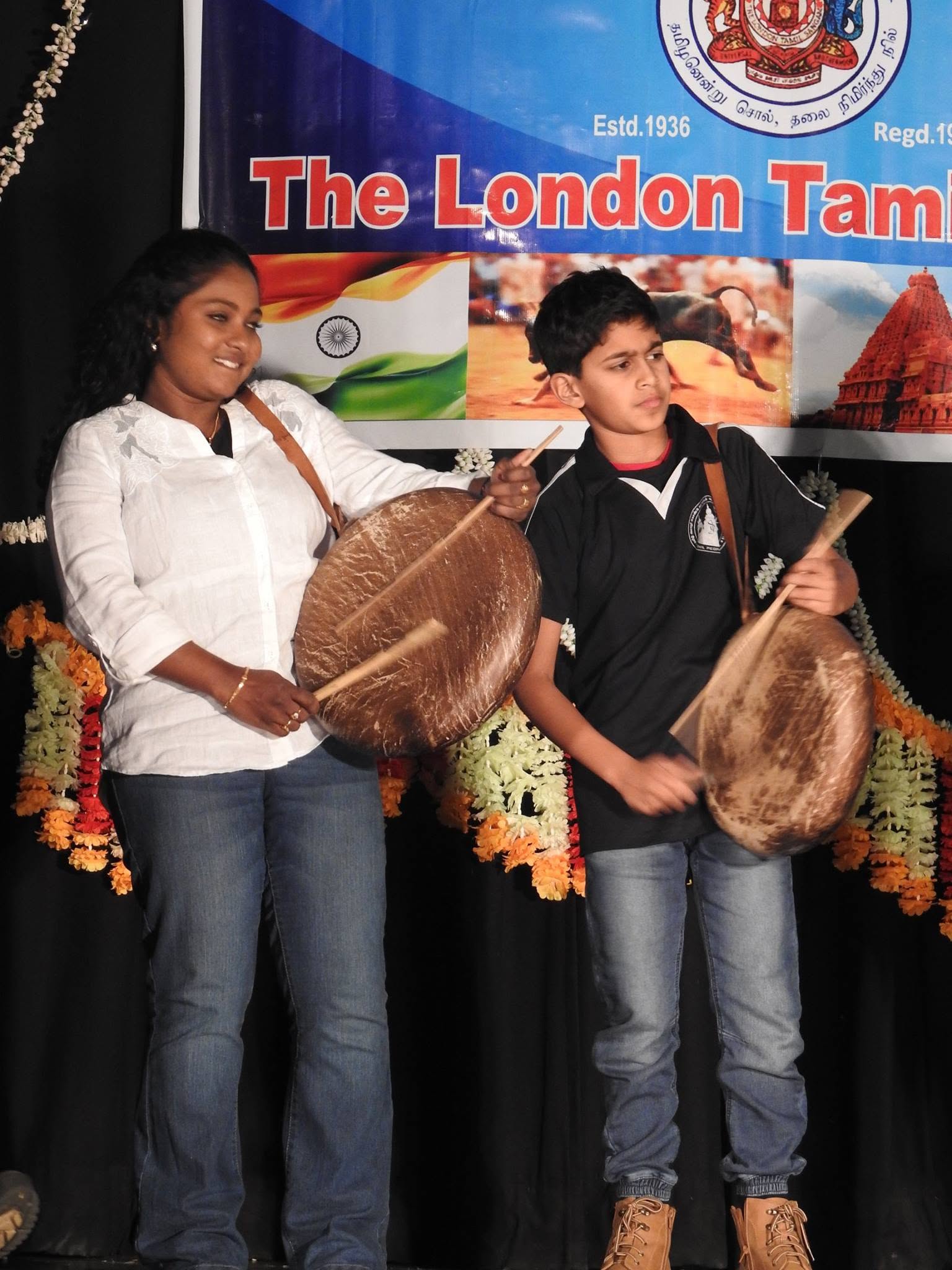 Two young performers holding frame drums on stage