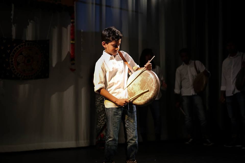 Young boy playing a parai drum on stage during a Tamil Arts UK performance